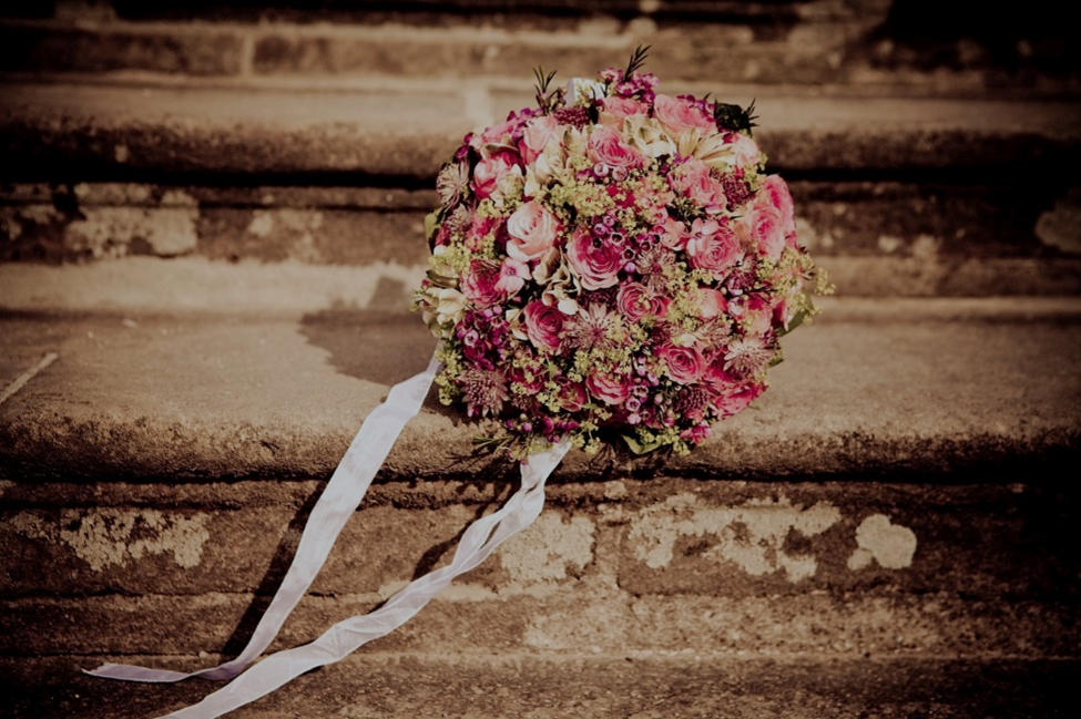 Een bruidsboeket met roze bloemen ligt op een trap.